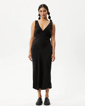 Load image into Gallery viewer, the Afends Women&#39;s Gemma Dress in Black on a model posing in front of a white background staring into the camera
