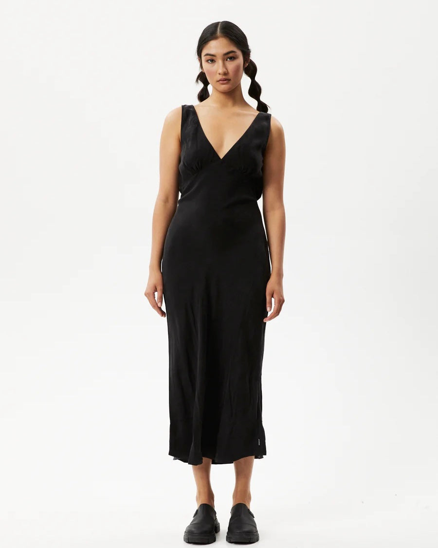 the Afends Women's Gemma Dress in Black on a model posing in front of a white background staring into the camera