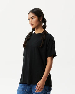 side angled view of the the Afends Women's Slay Oversized Tee in Black on a model posing against a white background