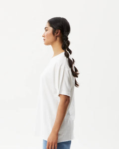 side view of the Afends Women's Slay Oversized Tee in White on a model posing in front of a white background