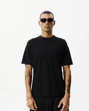 Load image into Gallery viewer, the Afends Men&#39;s Classic Hemp Retro Tee in Black on a model posing in front of a white background staring into the camera
