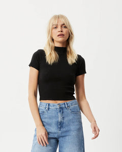 the Afends Women's Iconic Rib Tee in Black on a model posing in front of a white background