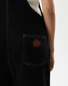 close up view of the back pocket detail of the the Afends Women's Louis Overalls in Washed Black on a model