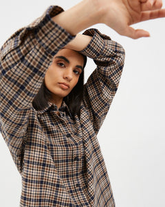 the Dr. Denim Women's Molly Shirt in Ocean Check on a model posing with her hands above her head looking straight into the camera