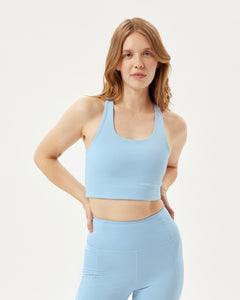 front view of the Girlfriend Collective Paloma Bra in Cerulean on a model posing with her hands on her waist