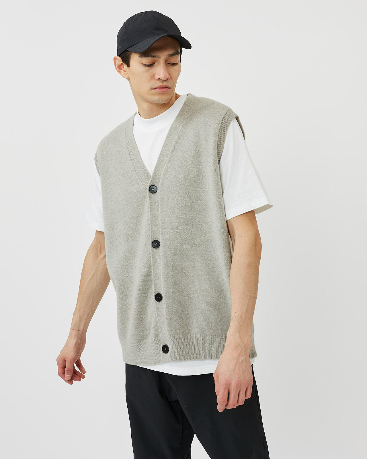 Minimum Men's Vastar Vest in Ghost Grey layered over a white t shirt pairing with a black cap