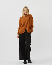 Load image into Gallery viewer, front view of a model standing wearing the Minimum Women&#39;s Meline Sweater in Roasted Pecan paired with wide leg black pants and shiny black shoes
