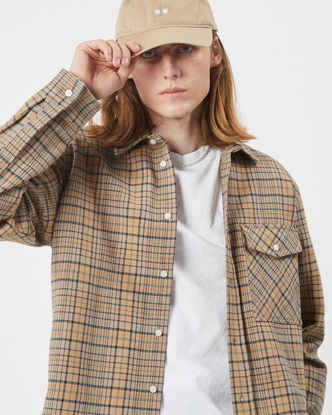the Minimum Men's Woad Overshirt in Brown Sugar on a model posing with his hand on the brim of his hat