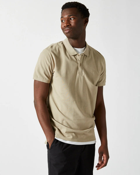 the Minimum Men's Zane Polo in Seneca Rock on a model posing with one hand in his pocket looking over his shoulder