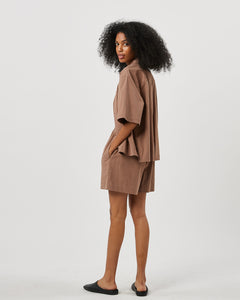 the back view of the Minimum Women's Luinna Shirt in Brownie on a model posing to the side looking over her shoulder