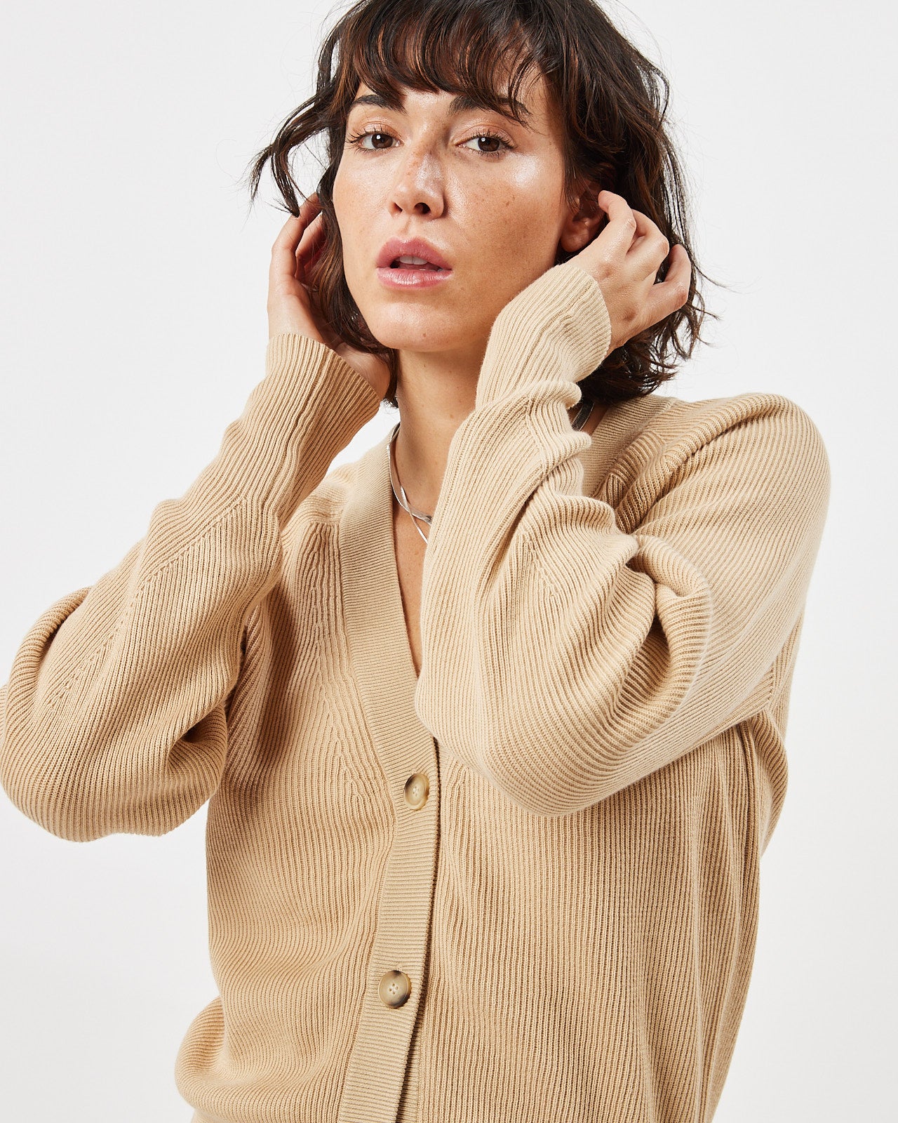 close up of the Minimum Women's Cardine Cardigan in Safari on a model posing with her hands in her hair