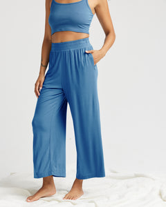 close up of model wearing the Richer Poorer Women's Night Knit Pant in Blue Horizon posing with her left hand in her pocket against a white background wearing a matching tank top