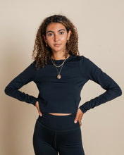 Load image into Gallery viewer, the Girlfriend Collective ReSet Long Sleeve Tee in Black worn by a model posing with her hands on her hips
