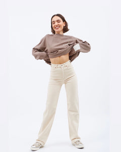 Dr. Denim Women's Moxy Jean in Loom State on a model posing holding her sweatshirt up above her waist