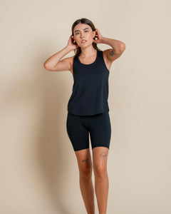 the Girlfriend Collective ReSet Bike Short in Black on a model posing with her hands in her hair
