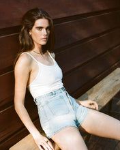 Load image into Gallery viewer, a model sitting casually on a bench leaning against a wood wall wearing the Rolla&#39;s Women&#39;s Mirage Sailor Short in Light Blue
