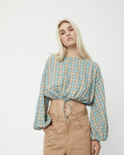Load image into Gallery viewer, the Afends Women&#39;s Millie Blouse in Tan Check on a model posing with her hand in her pocket
