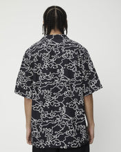 Load image into Gallery viewer, a close up of the back view of the Afends Men&#39;s Script Short Sleeve Cuban Shirt in Black Camo on a model

