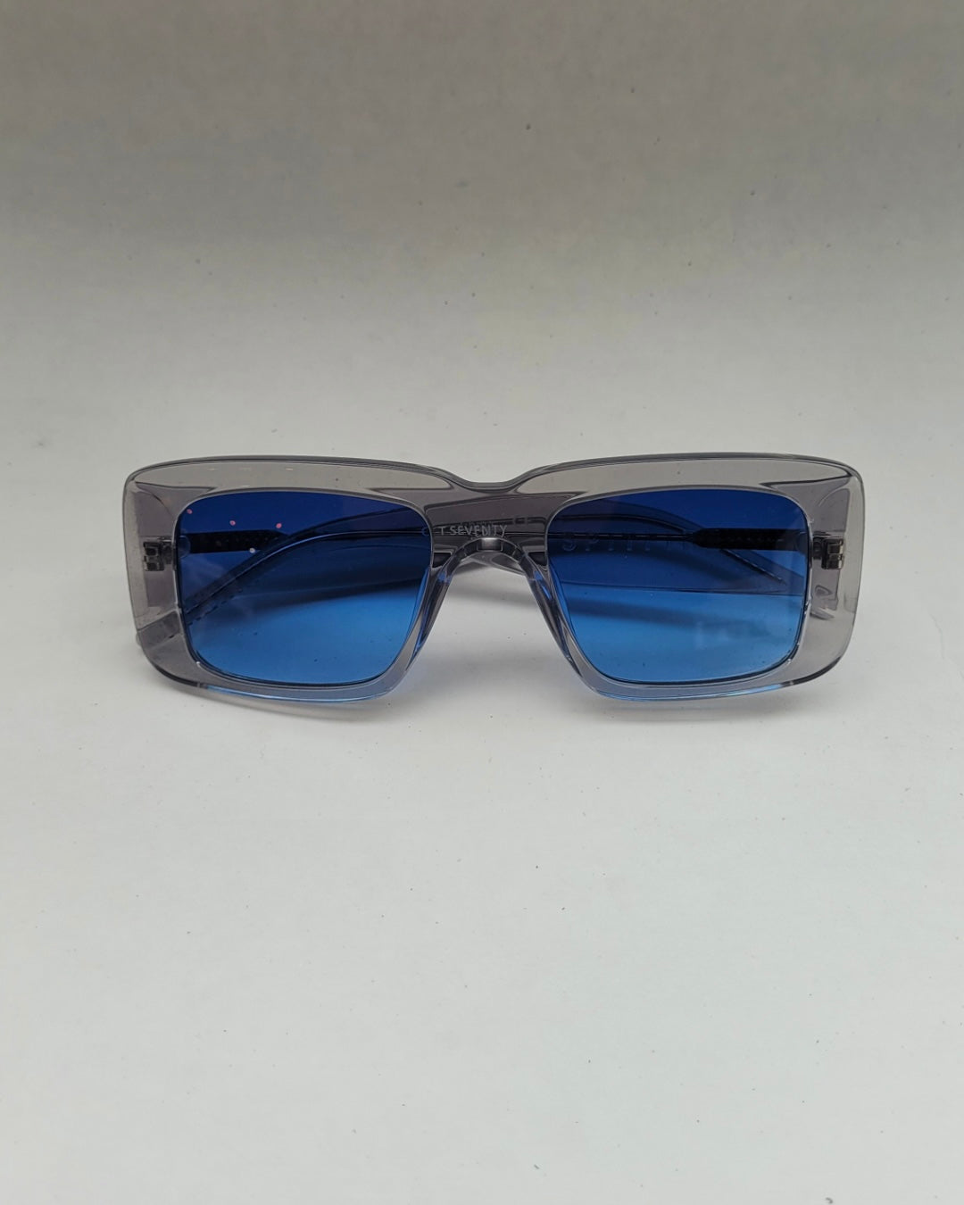 the Spitfire Cut Seventy Sunglasses in clear with blue lens laying on a neutral background