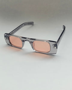 the Spitfire Cut Seven Sunglasses in grey with pink lens on an angle against a neutral background
