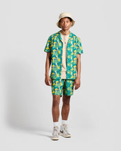 Load image into Gallery viewer, the Poplin &amp; Co Men&#39;s Camp Shirt in Banana Bunch worn open over a tshirt by a model paired with the matching shorts while standing against a neutral background
