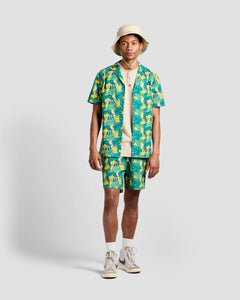 the Poplin & Co Men's Camp Shirt in Banana Bunch worn open over a tshirt by a model paired with the matching shorts while standing against a neutral background
