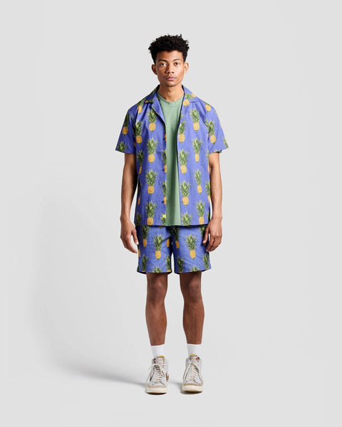 the Poplin & Co Men's Camp Shirt in Wild Pineapple worn open over a tshirt by a model standing facing the camera head on against a neutral background