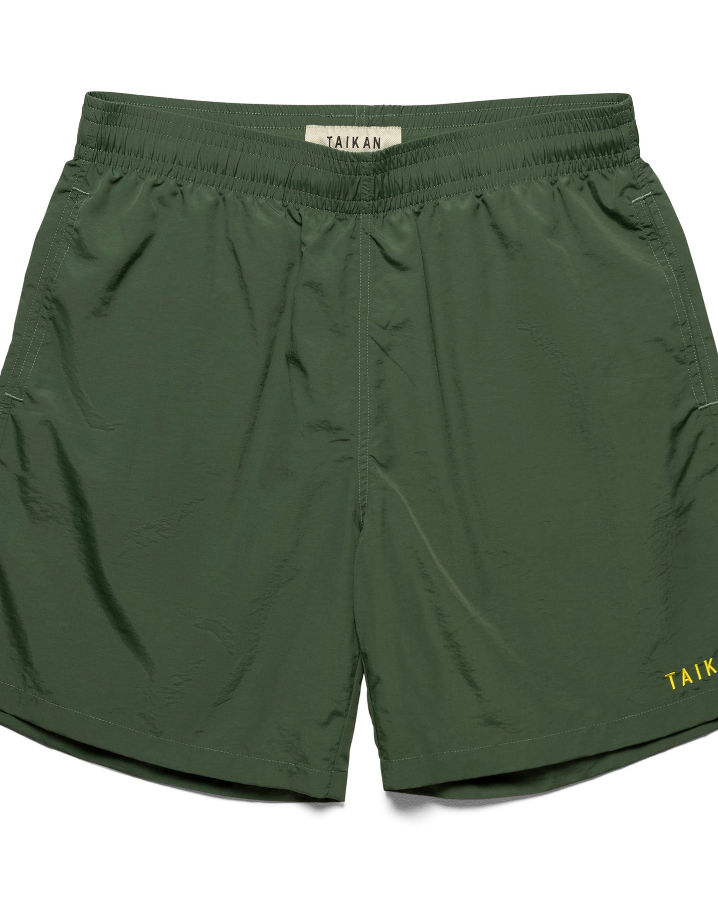 the Taikan Nylon Shorts in Forest Green laying flat on a white background
