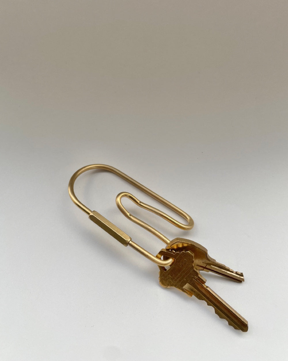 Belt Loop Key Chain in Brass with two keys against a neutral background