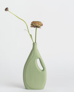 Middle Kingdom Laundry Detergent Vase in sage against white background with a flower