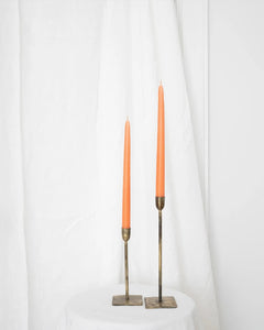 a pair of Socco Designs Taper Candles in peach in two tapers of varying heights against a white sheet background